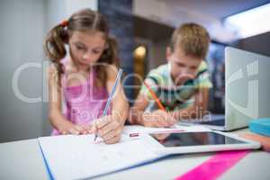 Siblings doing their homework in kitchen