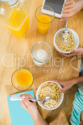 Sibling having breakfast cereal in kitchen