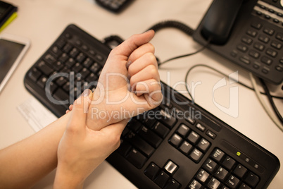 Cropped hands of tired businesswoman on office desk