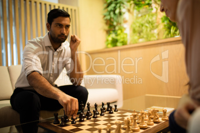Serious businessman playing chess with female colleague