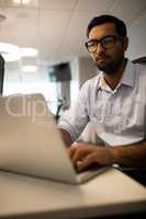 Young businessman working on laptop in office