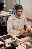 Businessman listening music through headphones while working at creative office