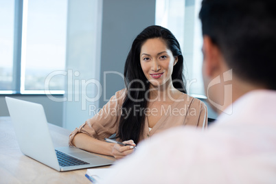 Young businesswoman sitting with male colleague in office