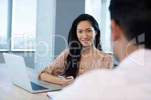 Young businesswoman sitting with male colleague in office