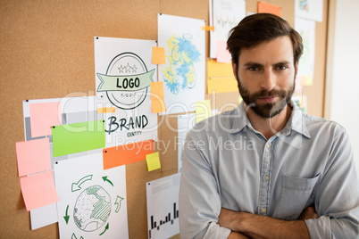 Businessman with arms crossed standing by soft board