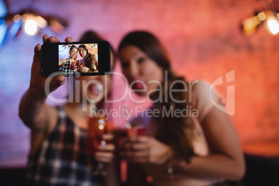 Young women taking a selfie while having cocktail drinks