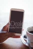 Hand of woman using mobile phone while having coffee