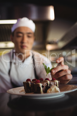 Male chef garnishing dessert plate