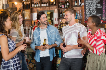 Friends holding beer bottles in pub
