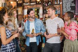 Friends holding beer bottles in pub