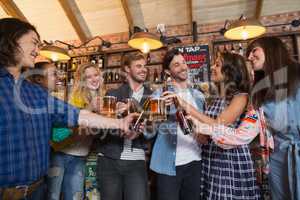 Happy friends toasting beer glasses and bottles in pub
