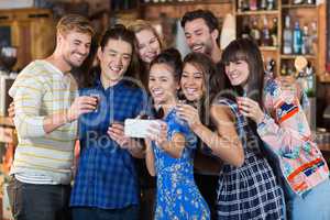 Cheerful friends taking selfie while holding short glasses