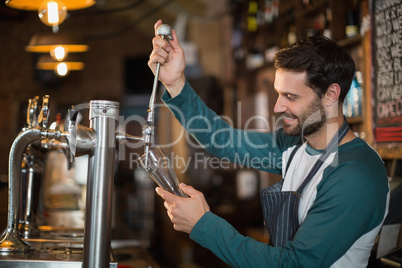 Happy bartender pouring beer from tap