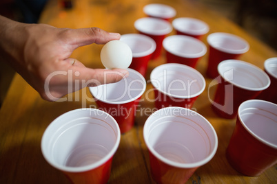 Cropped hand of man playing beer pong