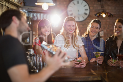 Friends looking at bartender making drinks