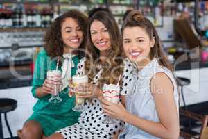 Smiling female friends holding drinks at restaurant