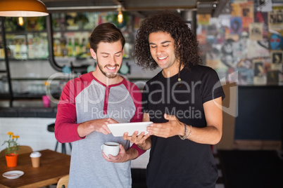 Smiling young friend using digital tablet in restaurant