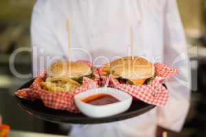 Close up of chef holding burgers in plate