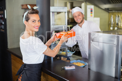 Chef giving burgers to waitress in commercial kitchen