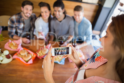 Young woman photographing friends in restaurant