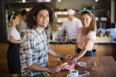 Waitress serving burger to young man in restaurant