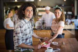 Waitress serving burger to young man in restaurant