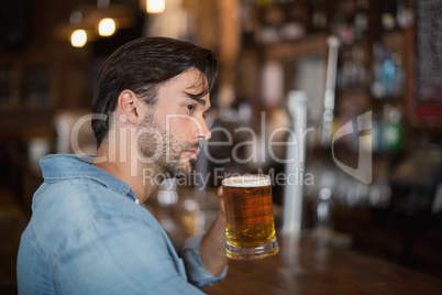 Man looking away while drink beer at pub