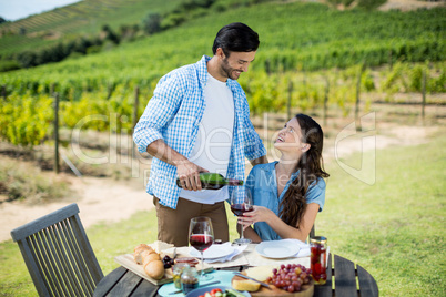 Happy looking at woman while pouring red wine in glass