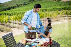 Happy looking at woman while pouring red wine in glass