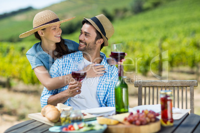 Happy couple with red wine glasses looking at each