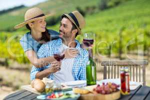 Happy couple with red wine glasses looking at each