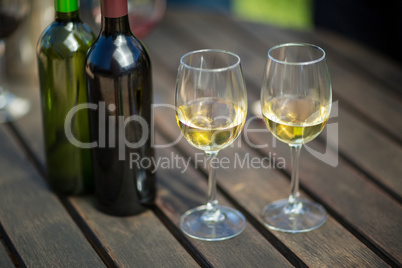White wine in glasses by bottles on table