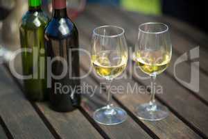 White wine in glasses by bottles on table