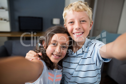 Siblings taking selfie in living room