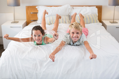 Portrait of smiling siblings having fun on bed