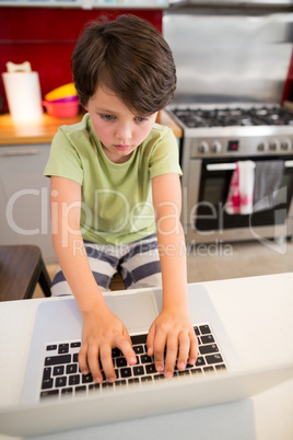 Boy using laptop in kitchen