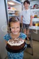 Portrait of girl holding cake in kitchen