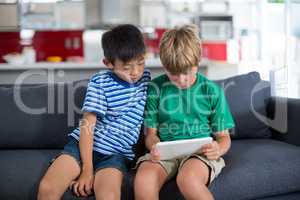 Siblings using digital tablet in living room