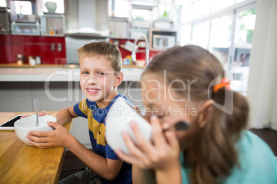 Sibling having breakfast cereal in kitchen