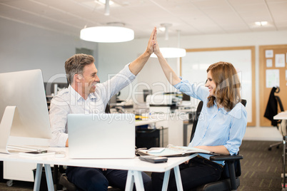 Happy business colleagues giving high five to each other