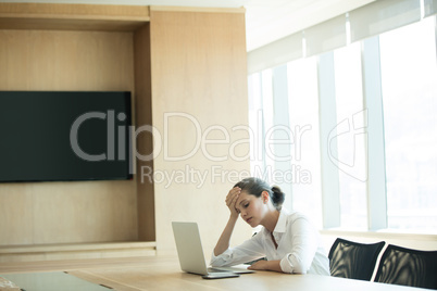 Worried businesswoman using laptop in conference room