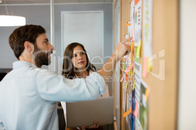 Young businessman with female colleague discussing over charts at office