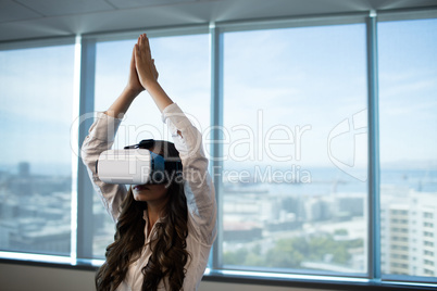 Businesswoman practicing yoga with arms raised while using virtual reality glasses
