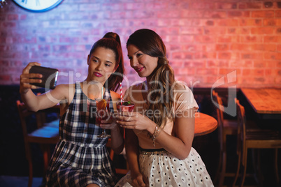 Young women taking a selfie while having cocktail drinks