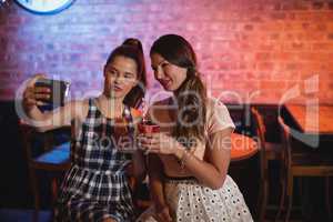 Young women taking a selfie while having cocktail drinks