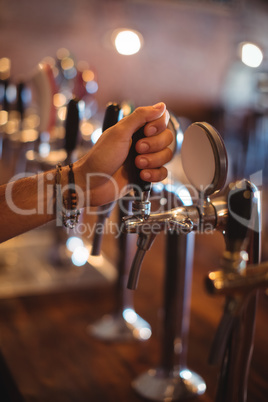 Bartender hands using beer tap in pub