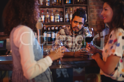 Young women interacting with bartender at counter