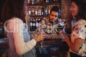 Young women interacting with bartender at counter