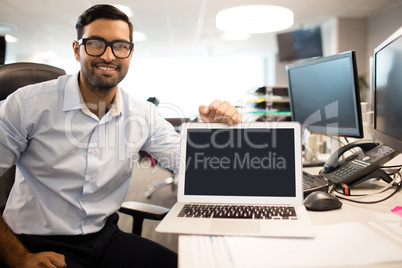 Portrait of smiling businessman with laptop in office