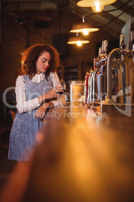 Thoughtful woman having red wine at counter